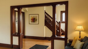 A wooden interior with a staircase, a framed artwork, a lamp, and a couch.