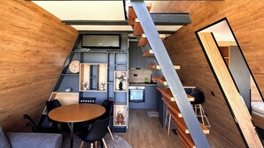 Un intérieur moderne avec un plafond en bois, un escalier, un coin repas avec une table ronde et des chaises, et un espace cuisine.