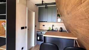 Une cuisine moderne avec un îlot central en bois, des tabourets de bar noirs et un four encastré.