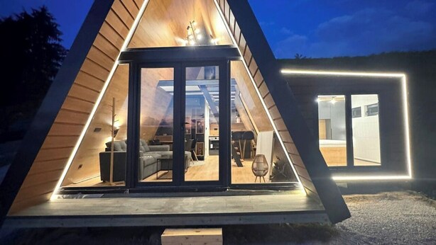 Un bâtiment moderne de forme triangulaire, doté d’une entrée en verre et d’un intérieur visible avec du mobilier.