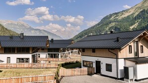 A modern chalet with a wooden deck, large windows, and a view of mountains. - Bichlbach Chalet With Sauna (Bichlbach)