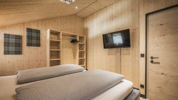A wooden-paneled room with a bed, a television, and built-in shelving.