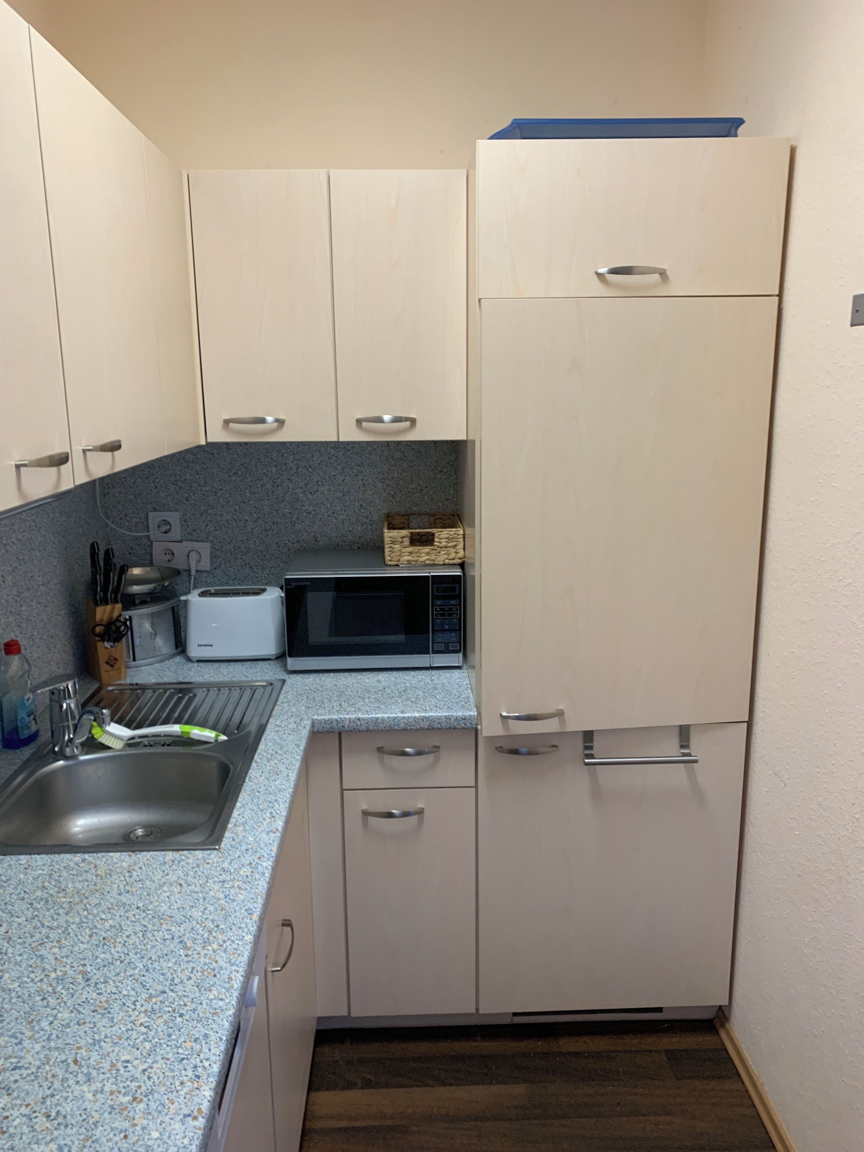 Cozinha compacta com micro-ondas, torradeira e pia.