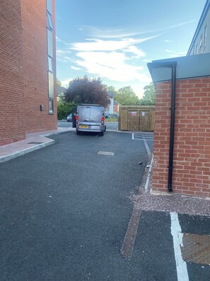 A parking area with a van parked in front of a building with a brick facade. - Ideal stay for contractors in Wolverhampton. Free parking! Close to city centre! (Wolverhampton)