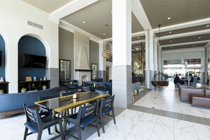 A spacious dining area with a high ceiling, modern lighting fixtures, and a large seating arrangement.