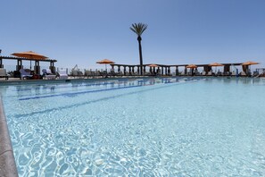A swimming pool with clear water, surrounded by lounge chairs and umbrellas.