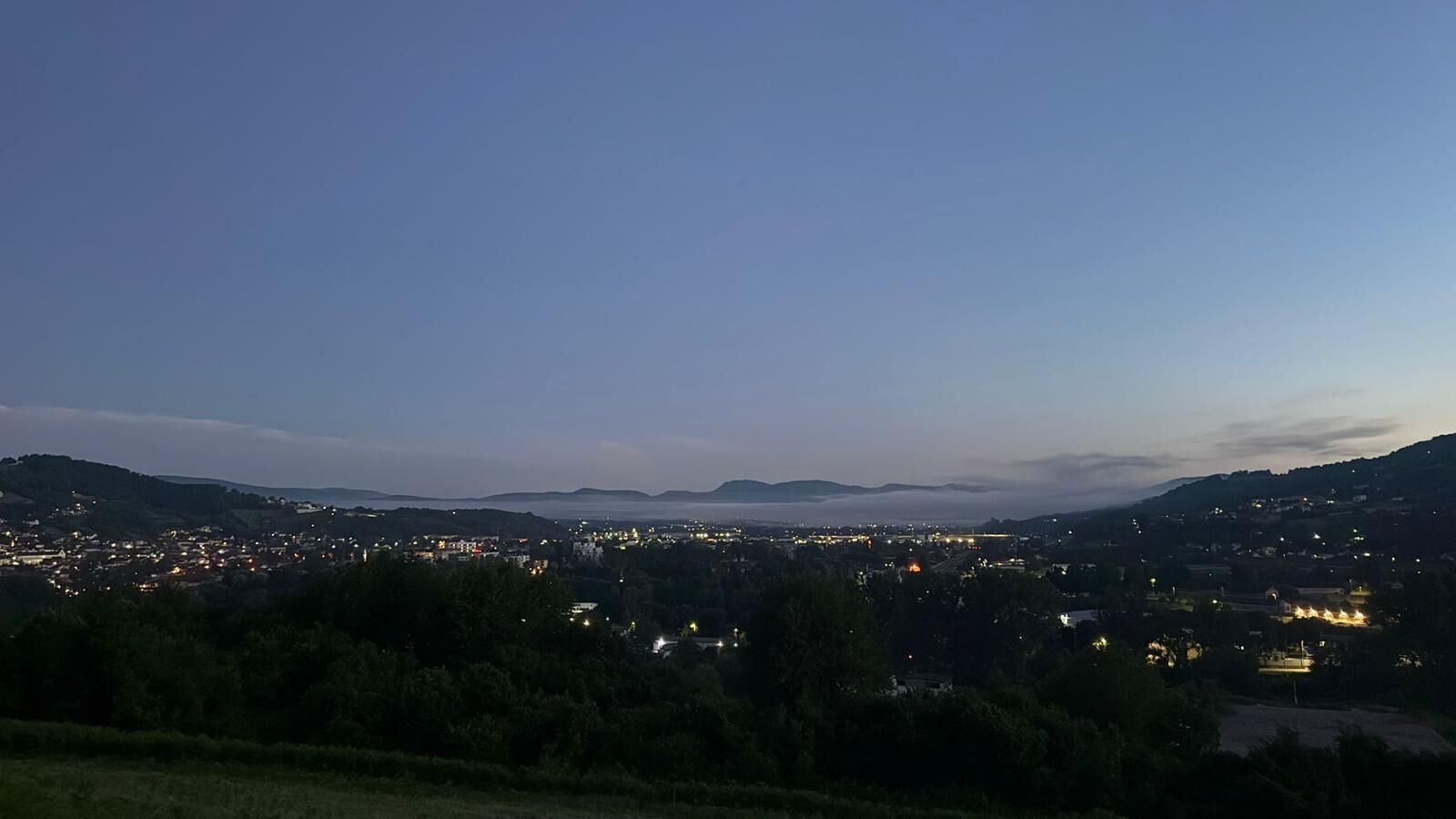A nighttime view of a city with distant mountains and a clear sky.