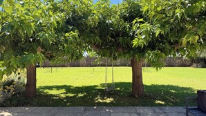 A park with a swing set, a grassy area, and trees.