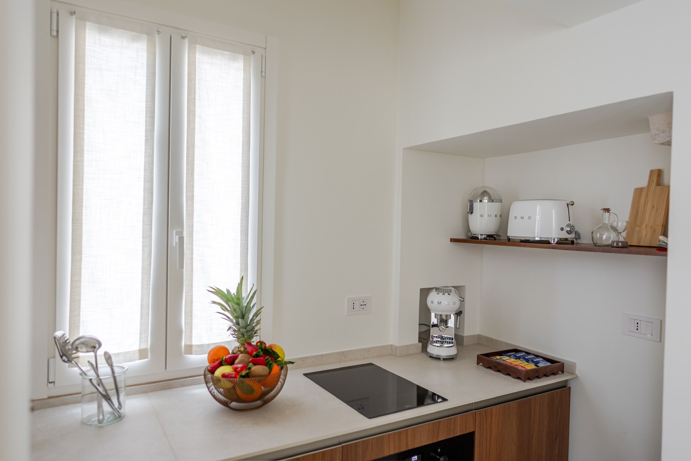 A kitchen with a fruit bowl, a coffee maker, and a toaster on the counter.