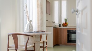 Uma sala de jantar com mesa, cadeiras, um vaso e uma janela com cortinas.
