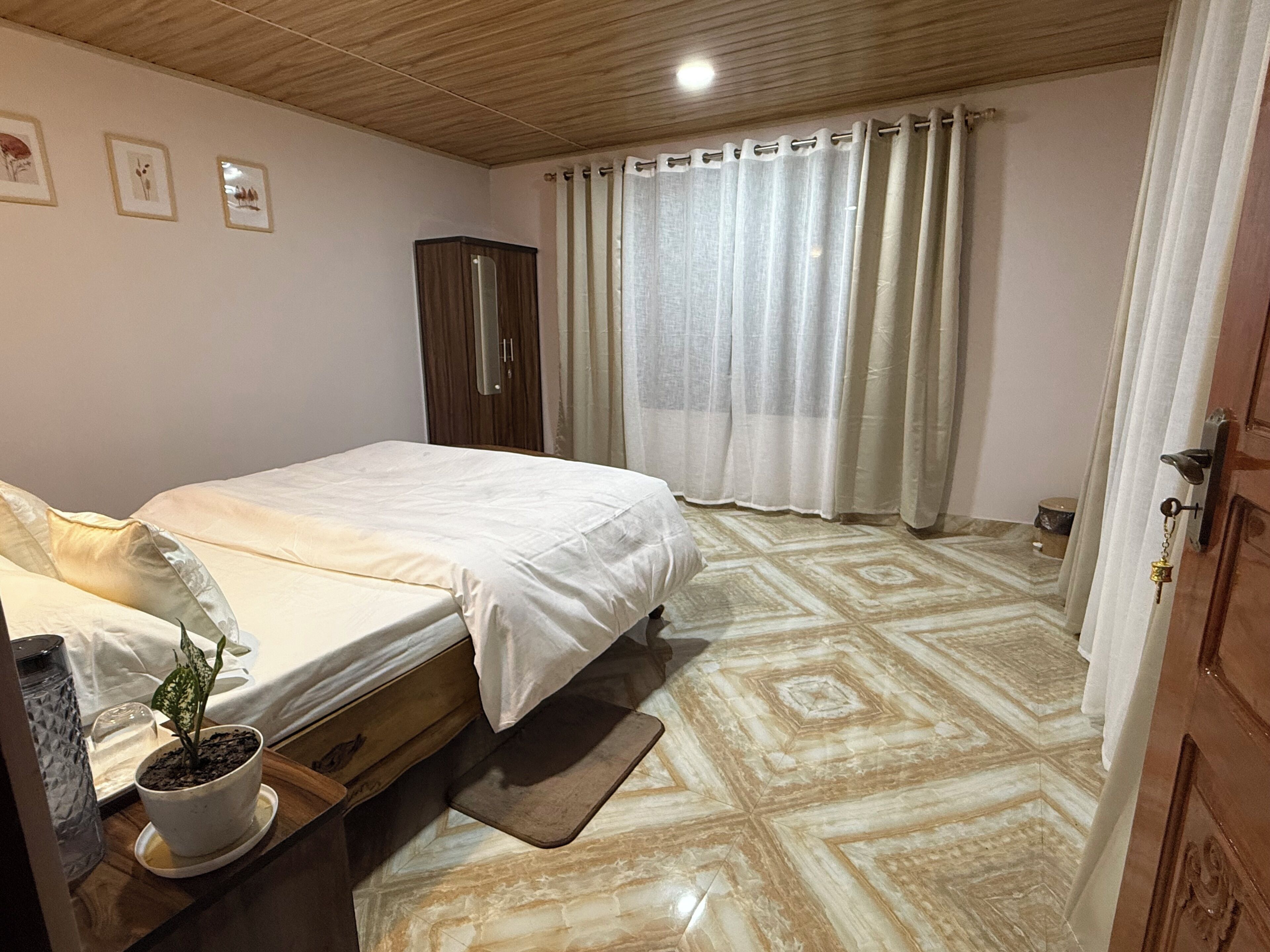 Un dormitorio con cama, una planta en maceta, un armario de madera y suelo estampado.