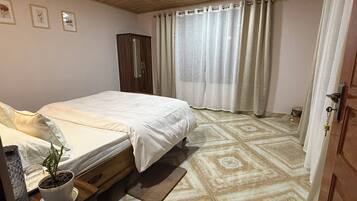 Un dormitorio con cama, una planta en maceta, un armario de madera y suelo estampado.