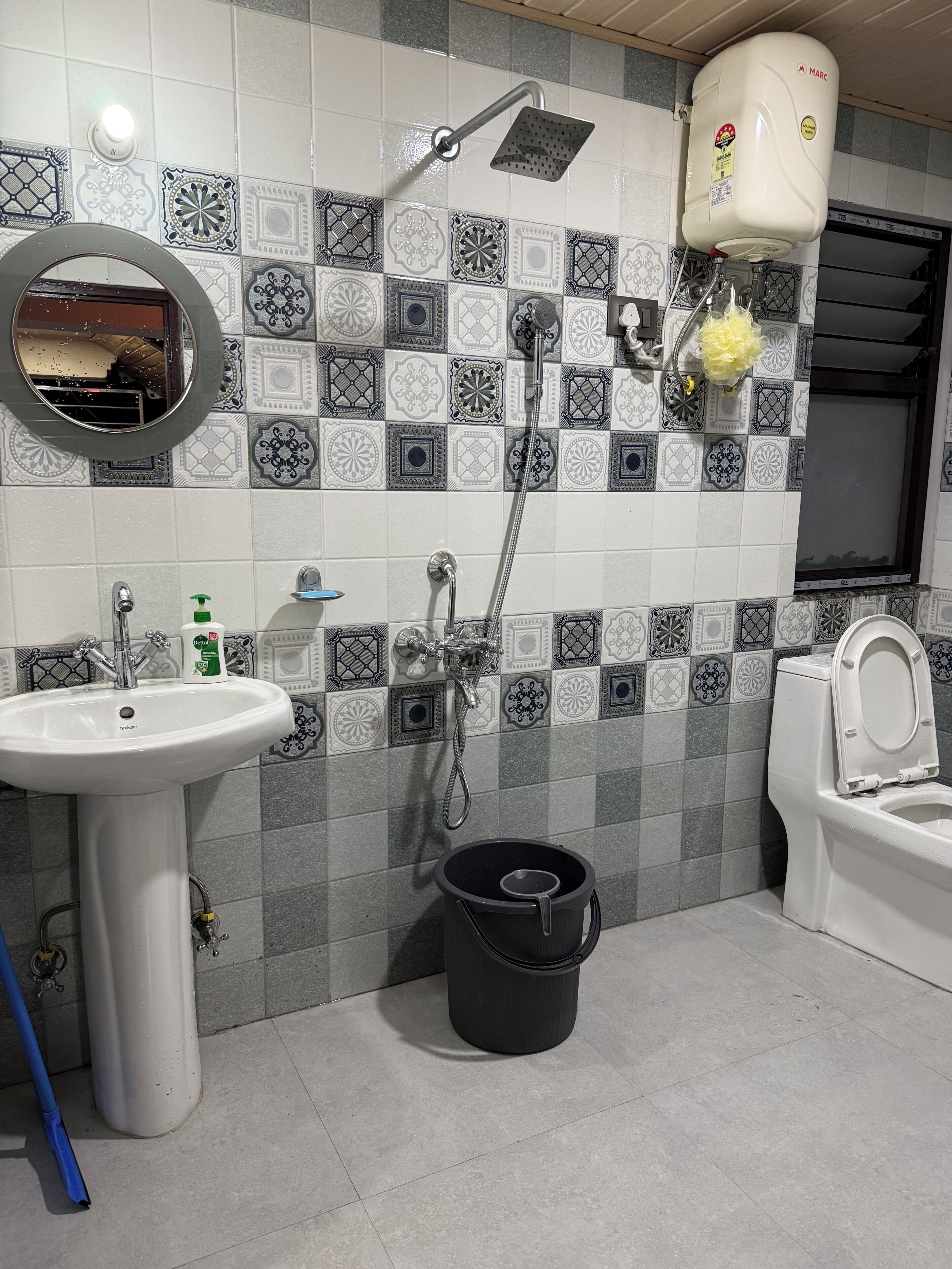 A bathroom with a sink, toilet, shower, and a decorative tiled wall.