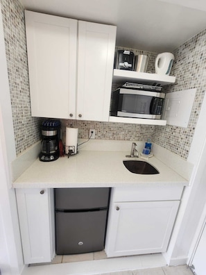 A compact kitchen with a microwave, coffee maker, and a sink. - 9th Floor Studio in the Middle of Waikiki (Honolulu)