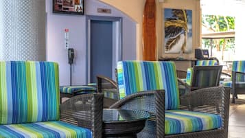 Wicker chairs with striped cushions, a wooden surfboard, and a framed picture on the wall.