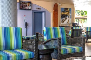 Wicker chairs with striped cushions, a wooden surfboard, and a framed picture on the wall. - 9th Floor Studio in the Middle of Waikiki (Honolulu)