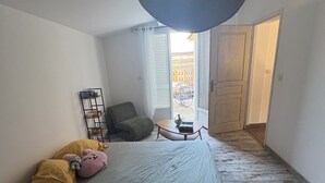 Une chambre à coucher avec un lit, une chaise, une petite table et une fenêtre.