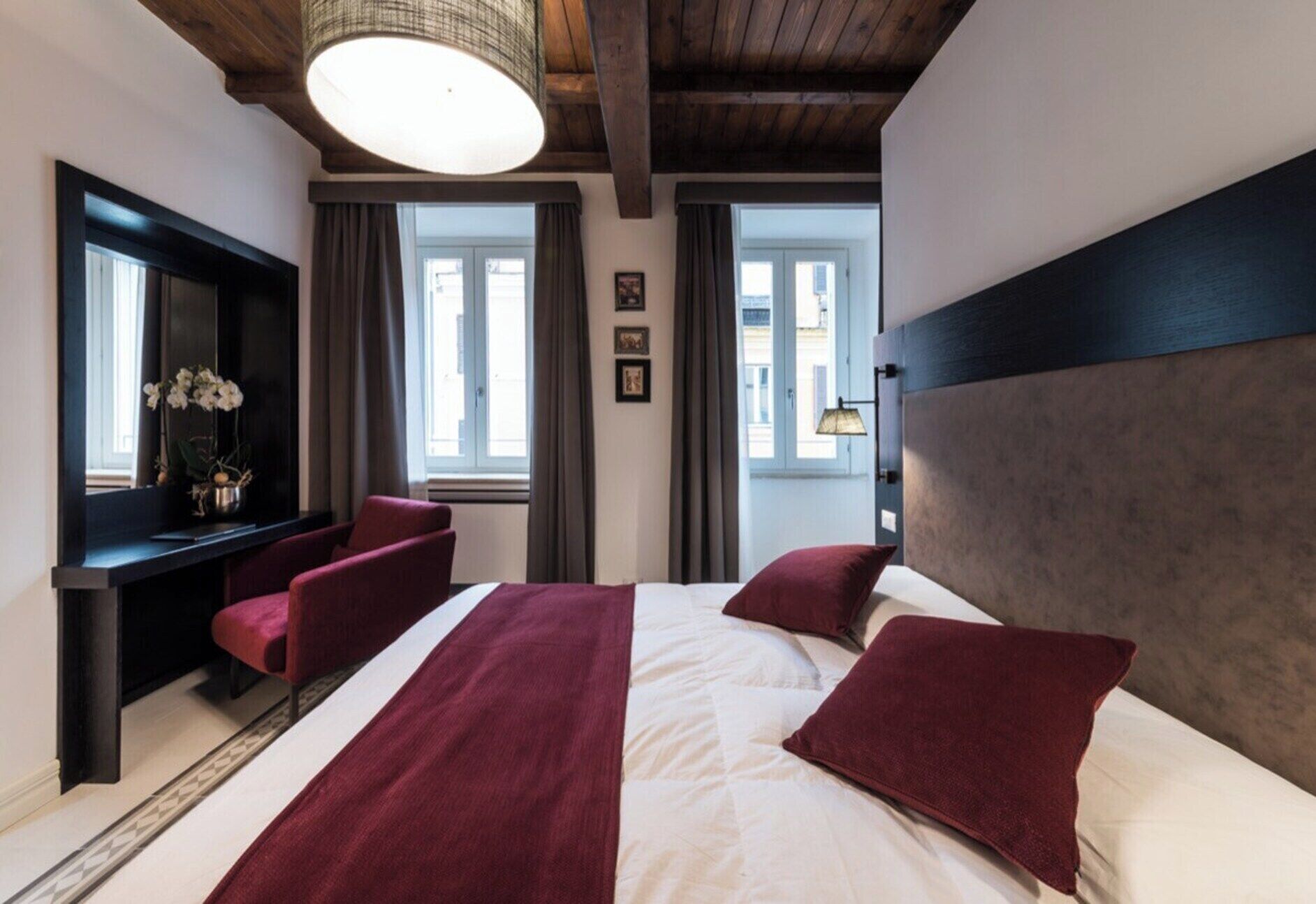 A hotel room with a bed, a desk, a chair, and a large window.