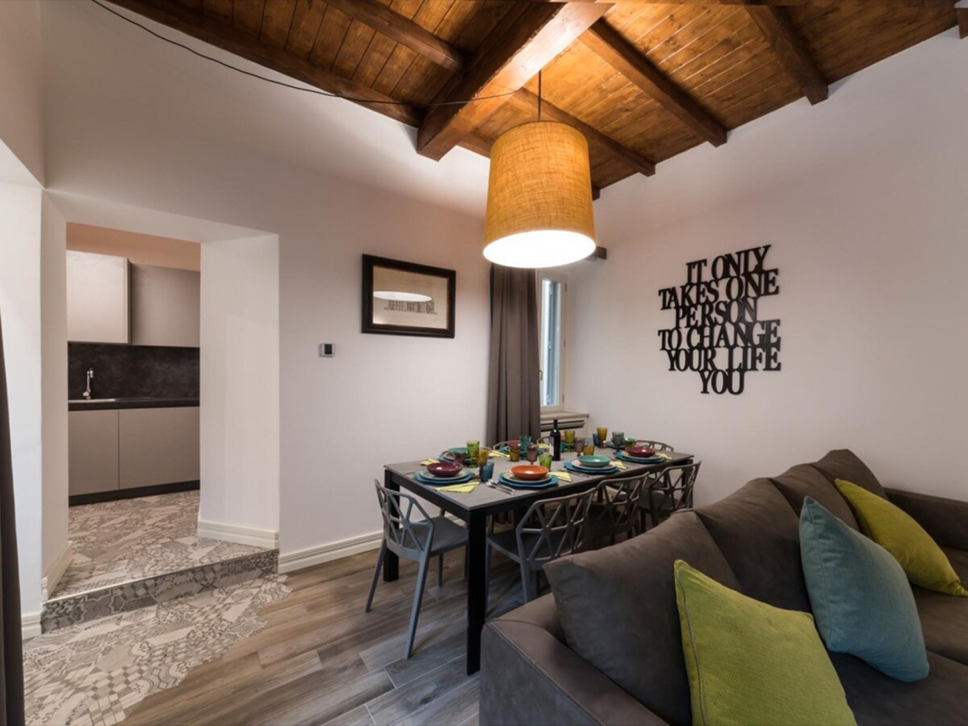 Ein modernes Interieur mit Essbereich, einer Couch und einer Decke mit freiliegenden Balken.