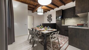 A modern kitchen with dark cabinetry, a white countertop, and a hanging light fixture. - Dolcevita Apartments (Roma)