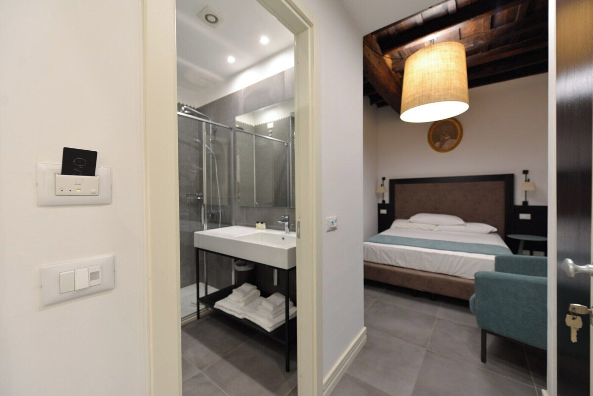 A modern hotel room with a shower, sink, and a bed with a headboard.