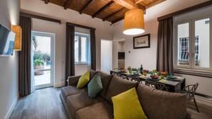 A modern living room with a brown sofa, a dining table, and a wooden ceiling. - Dolcevita Apartments (Roma)