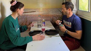 A dining area with a table, a bottle, a glass, and a can. - Naéco's Tiny Room (Plouharnel)