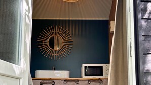 A small bathroom with a white sink, a microwave, and a decorative mirror. - Naéco's Tiny Room (Plouharnel)