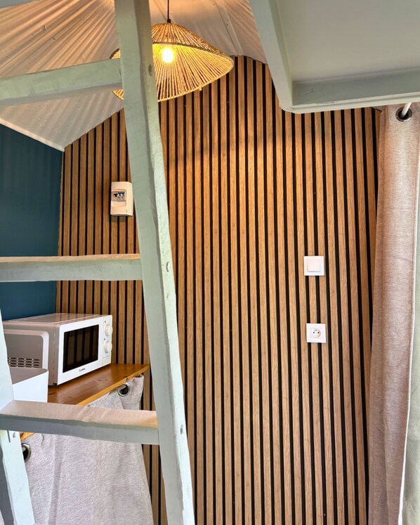 A room with a striped wall, a ceiling fan, a microwave, and a power outlet.