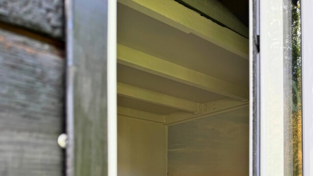 A bedroom with a bed, a window, and a wooden exterior wall. - Naéco's Tiny Room (Plouharnel)