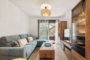 A modern living room with a sectional sofa, a wooden coffee table, a TV, and a sliding glass door leading to an outdoor area. - LXR Luna Blanca Suites (2 Bedrooms) Near the Sea (Fuengirola)