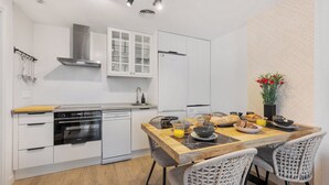 Uma cozinha moderna com armários brancos, uma mesa de jantar de madeira e uma mesa para café da manhã.