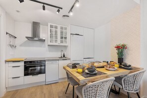 A modern kitchen with white cabinetry, a wooden dining table, and a breakfast setting. - LXR Luna Blanca Suites (2 Bedrooms) Near the Sea (Fuengirola)