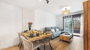 Uma sala de estar moderna com uma mesa de jantar, cadeiras de vime, um sofá e uma mesa de centro.