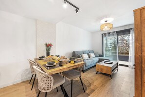 A modern living room with a dining table, wicker chairs, a sofa, and a coffee table. - LXR Luna Blanca Suites (2 Bedrooms) Near the Sea (Fuengirola)