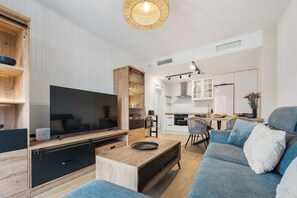 A modern living room with a flat-screen TV, wooden furniture, a dining area, and a kitchen. - LXR Luna Blanca Suites (2 Bedrooms) Near the Sea (Fuengirola)