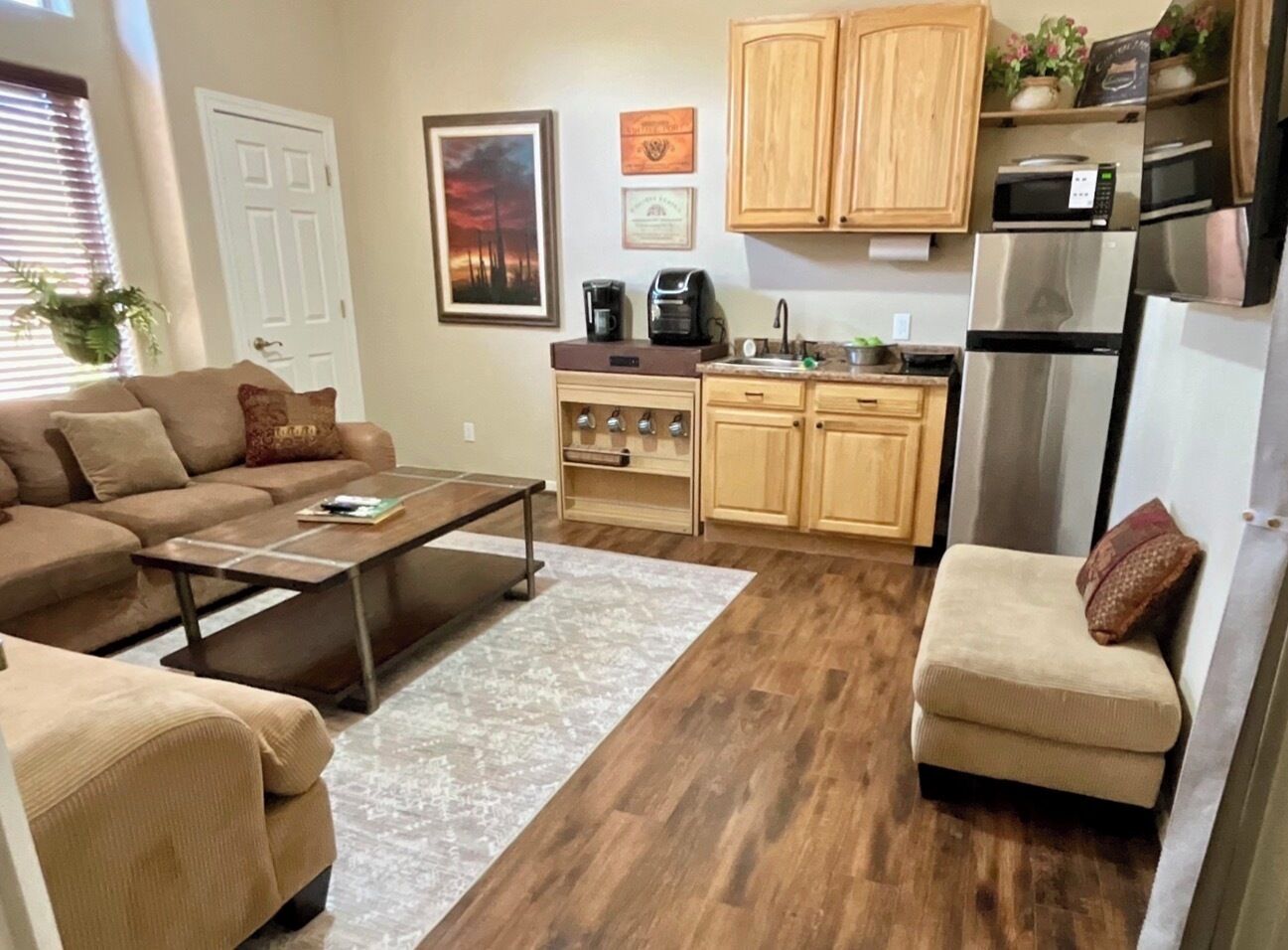 A compact living space with a sofa, coffee table, kitchenette, and a small seating area.