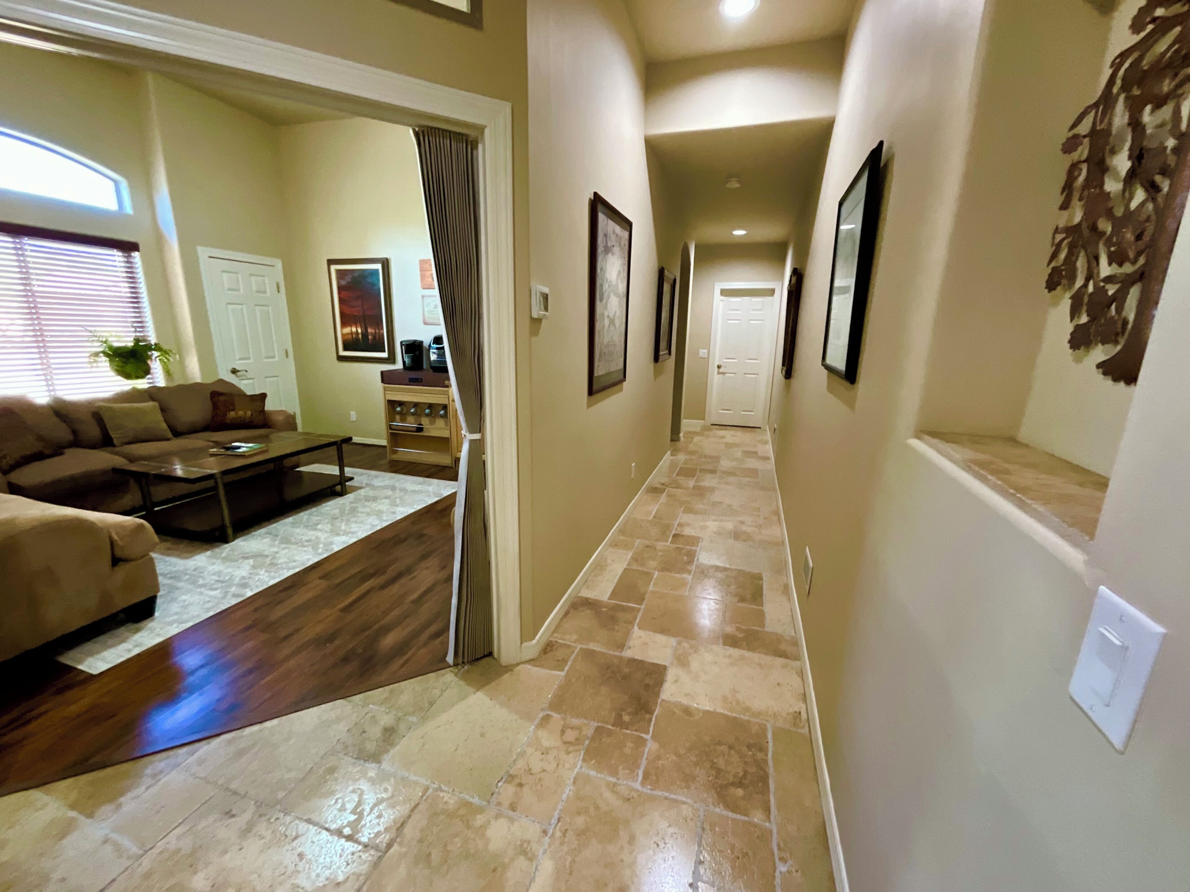 A hallway with a wooden floor, beige walls, and a door at the end.