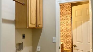 A room with a wooden cabinet, a white door, and a wall with a stone-like pattern.