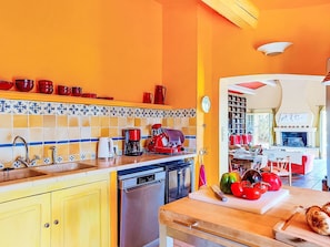 A kitchen with yellow cabinets, a dishwasher, a coffee maker, and a red appliance on the counter. - Grenouille by Interhome (Vence)
