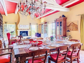 A dining area with a table set for four, a chandelier, and a fireplace. - Grenouille by Interhome (Vence)