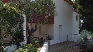 Um edifício branco com telhado vermelho, um deck de madeira e um caminho de pedra.