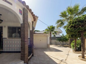Ein Wohnhaus mit geflieste Eingangsbereich, einer Garage und einem gepflegten Garten mit Palmen.