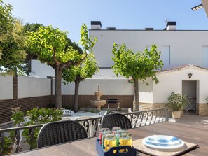 Eine Terrasse mit Außenmöbeln, einem Brunnen und einem weißen Gebäude im Hintergrund.
