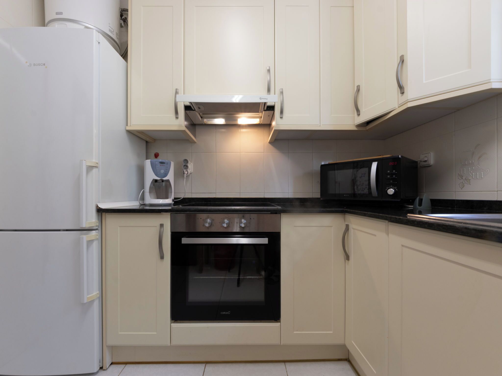 A kitchen with a Bosch refrigerator, a coffee maker, a microwave, and an oven.