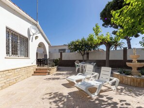 Un patio con mobiliario exterior, una antena parabólica y un árbol.