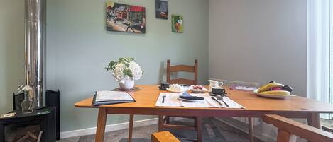 Un coin repas avec une table en bois, des chaises, un vase de fleurs et un tableau accroché au mur.