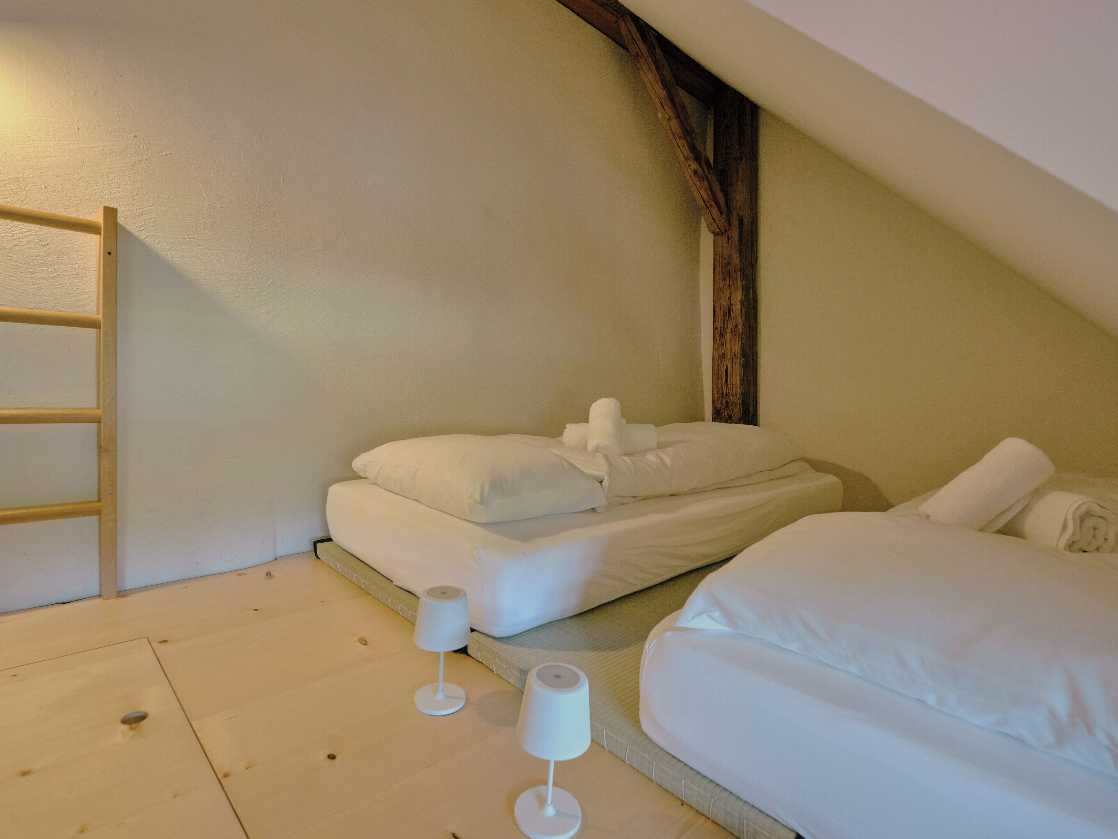 Una camera da letto con un letto a soppalco, una scala in legno e due lampade da comodino.