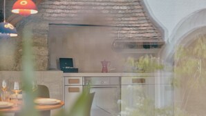 A modern kitchen with a stone wall, a black appliance, and a red pot on the counter. - Historic Landmark House near Rhine Falls, Schaffhausen & Lake Constance (Diessenhofen)