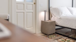 A room with a bed, a door, and a bedside table. - Garibaldi Luxury Suites - Graecalis (Noci)